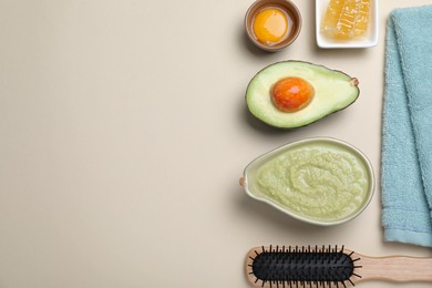 Homemade hair mask in bowl, ingredients, towel and wooden brush on beige background, flat lay. Space for text