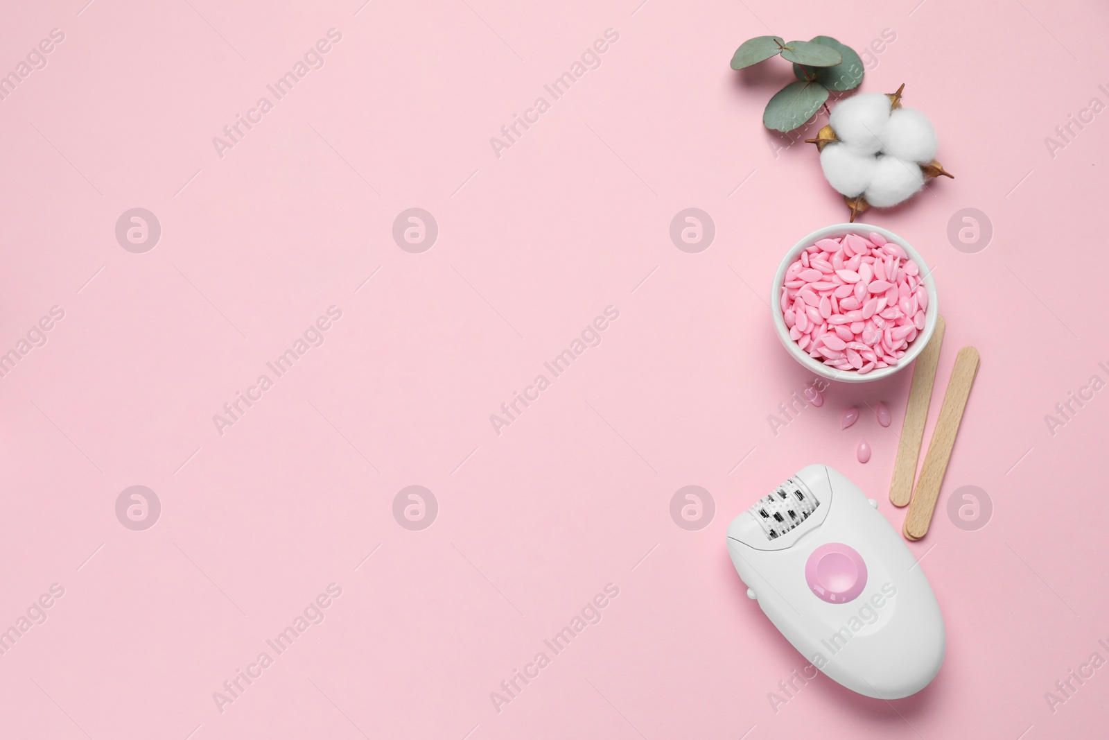 Photo of Modern epilator, depilatory wax and fluffy cotton flower on pink background, flat lay. Space for text
