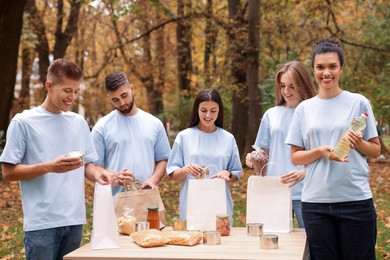 Photo of Group of volunteers packing food products at table in park