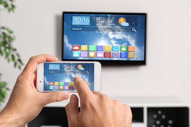 Image of Man using phone connected to smart TV in living room, closeup