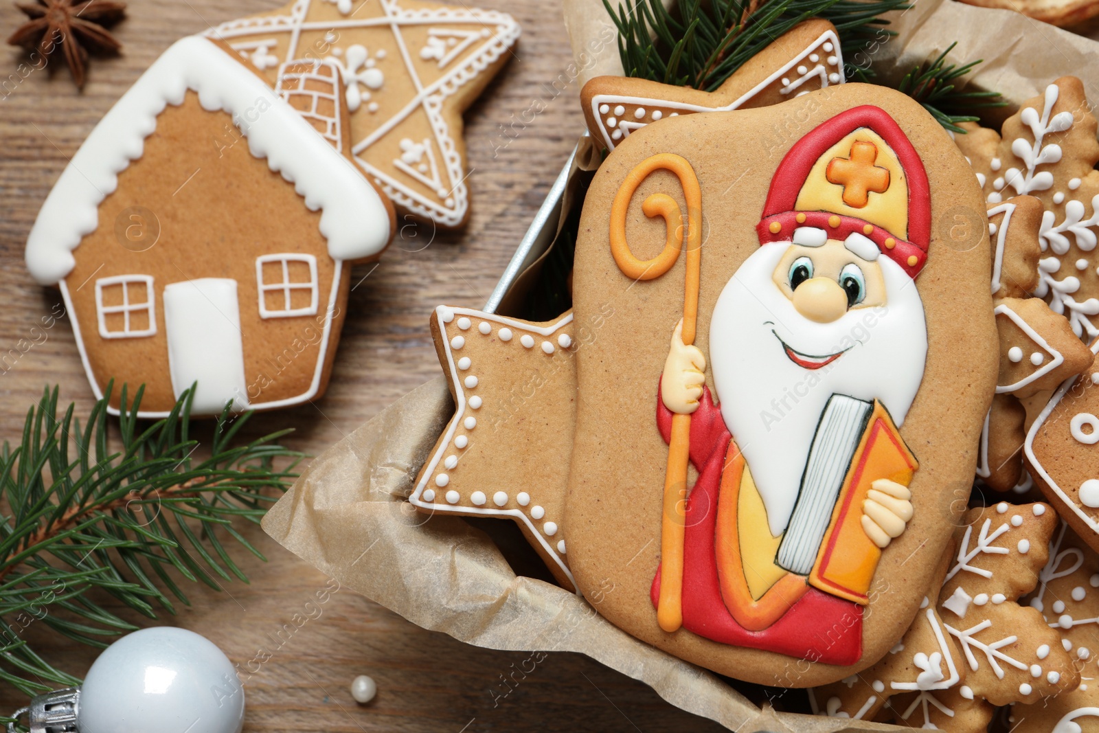 Photo of Tasty gingerbread cookies and festive decor on wooden table, flat lay. St. Nicholas Day celebration