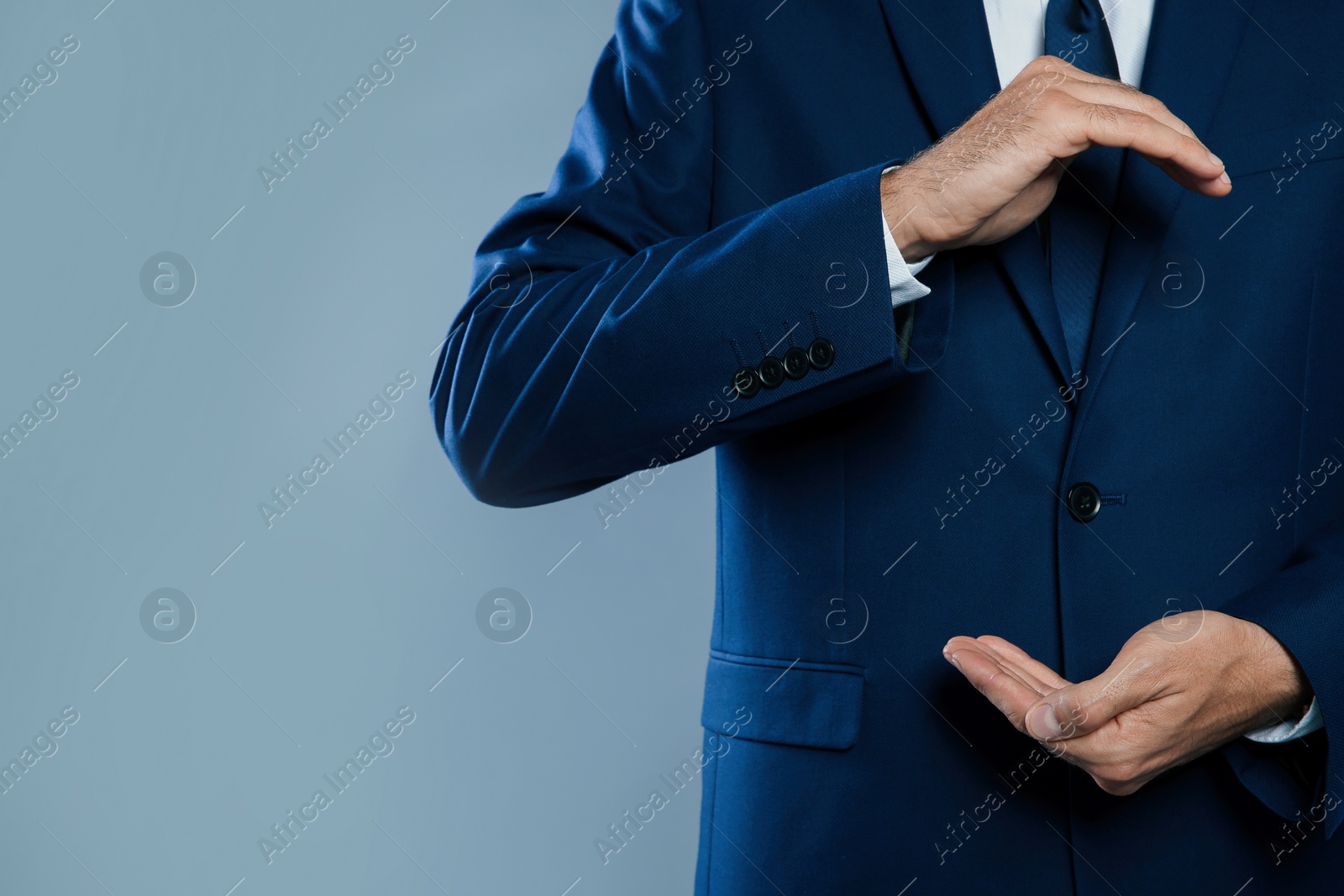 Photo of Businessman holding something on grey background, closeup view of hands with space for text