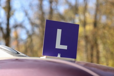 Photo of L-plate on car roof outdoors. Driving school