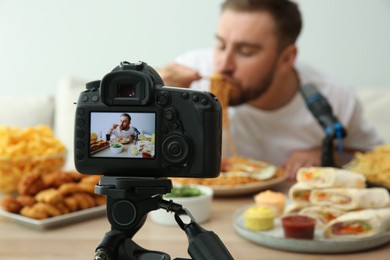 Photo of Food blogger recording eating show against light background, focus on camera screen. Mukbang vlog