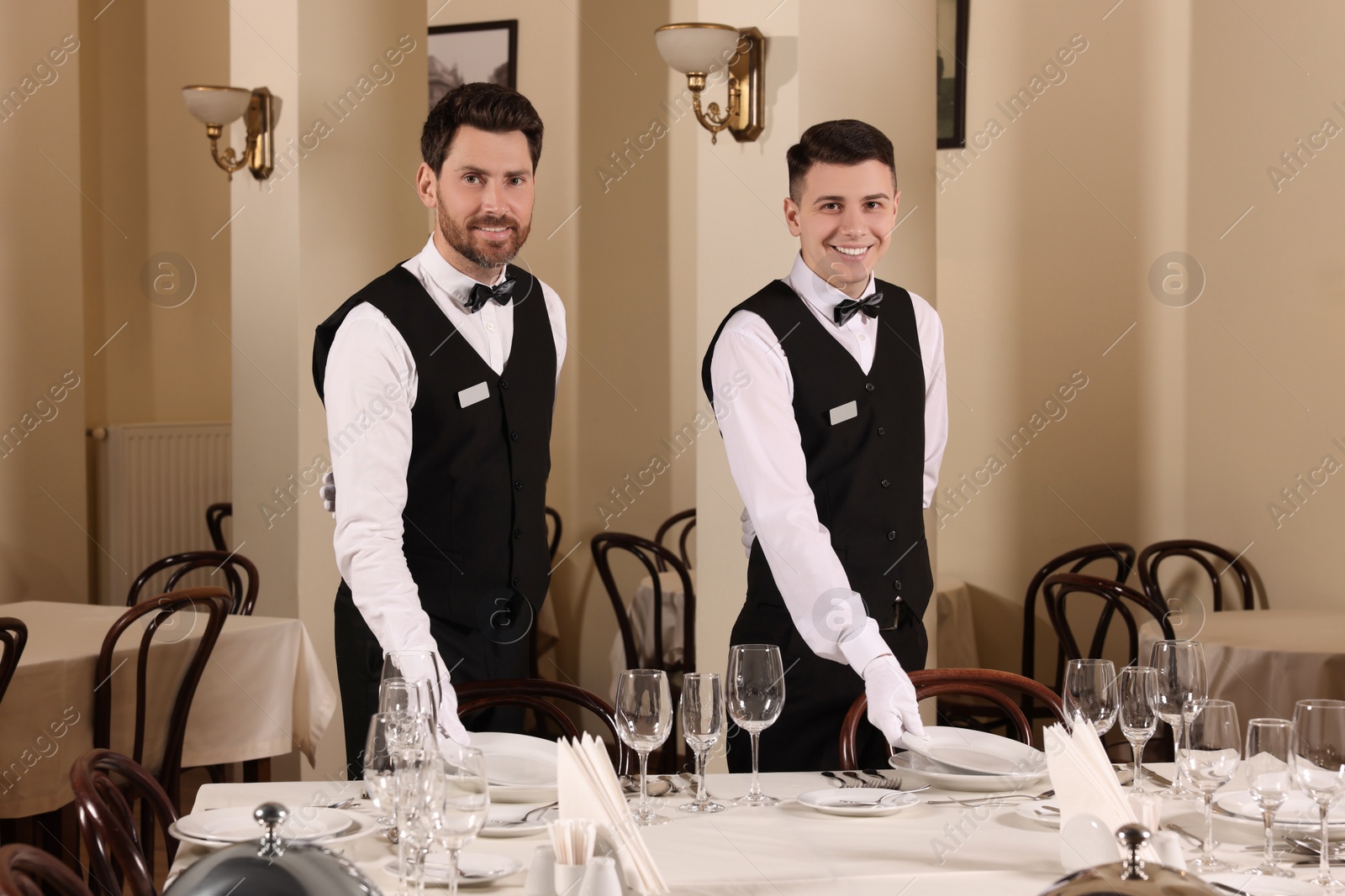 Photo of Men setting table in restaurant. Professional butler courses