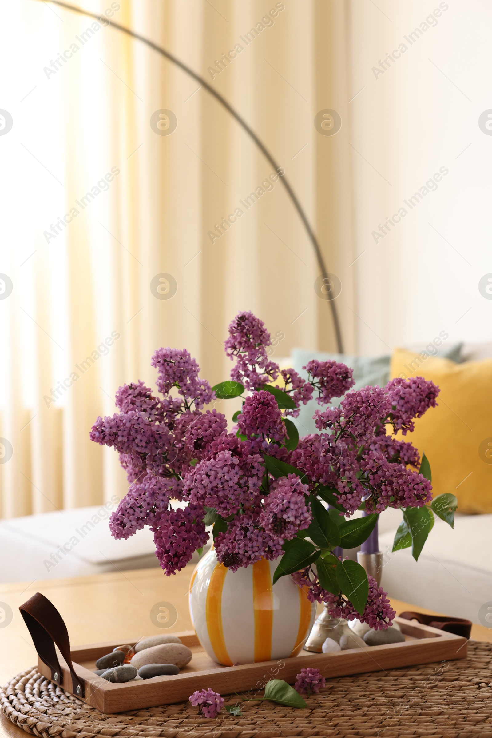 Photo of Beautiful fragrant lilac flowers in vase on table at home