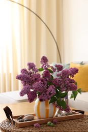 Photo of Beautiful fragrant lilac flowers in vase on table at home