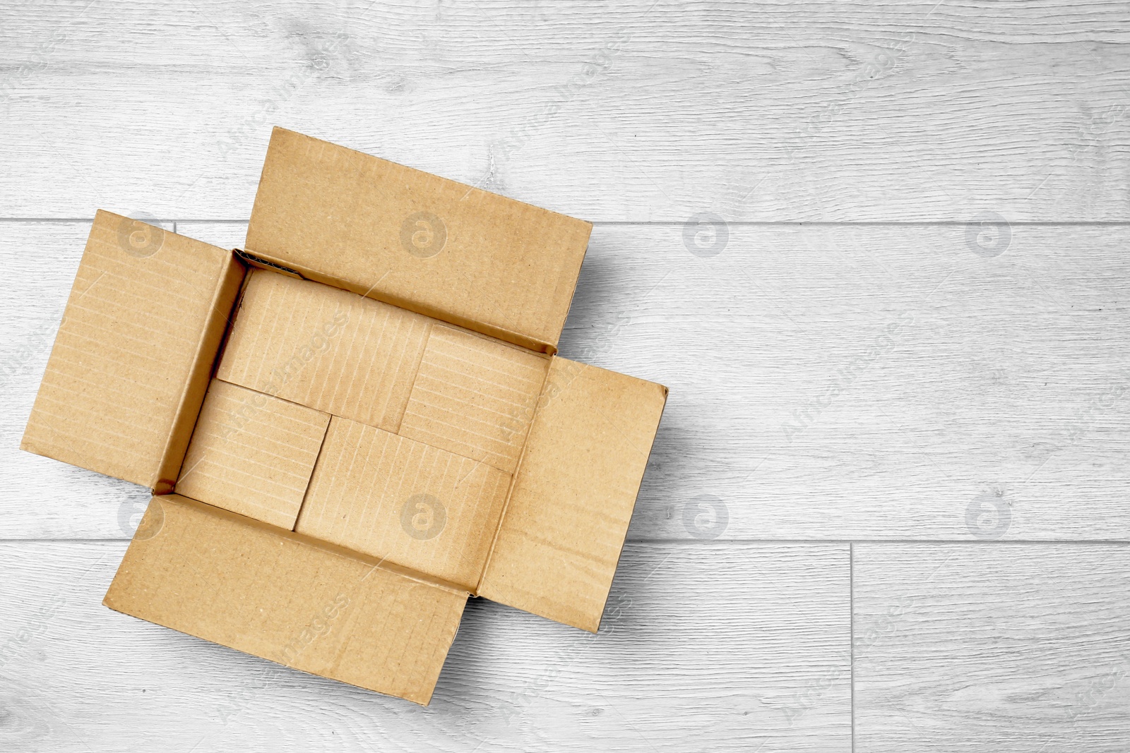 Photo of Open empty cardboard box on wooden floor