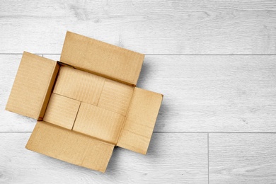 Photo of Open empty cardboard box on wooden floor