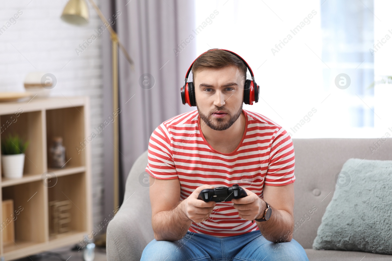 Photo of Young man playing video game at home