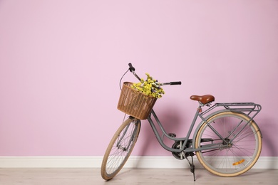 Photo of Retro bicycle with wicker basket near color wall