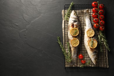 Photo of Baked fish with tomatoes, rosemary and lemon on black textured table, top view. Space for text