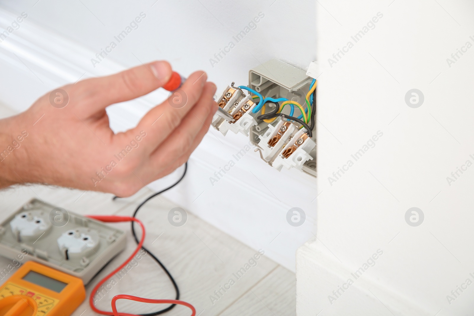 Photo of Electrician with neon-lamp tester checking voltage indoors, closeup