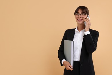 Happy secretary with folder talking on smartphone against beige background. Space for text