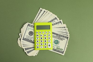 Money exchange. Dollar banknotes and calculator on green background, top view
