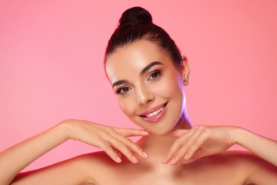 Photo of Portrait of young woman with beautiful makeup on light pink background