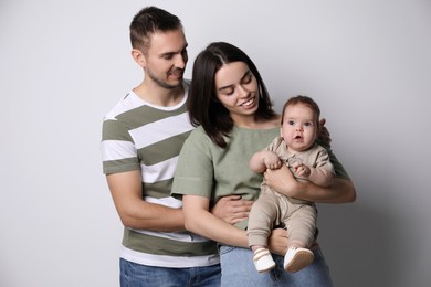 Happy family. Couple with their cute baby on grey background