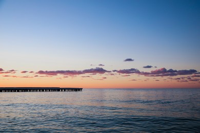 Photo of Picturesque view of pier in sea under beautiful sky at sunset