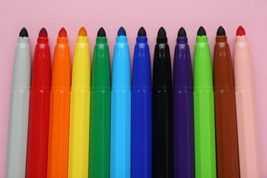 Photo of Many different colorful markers on light pink background, flat lay