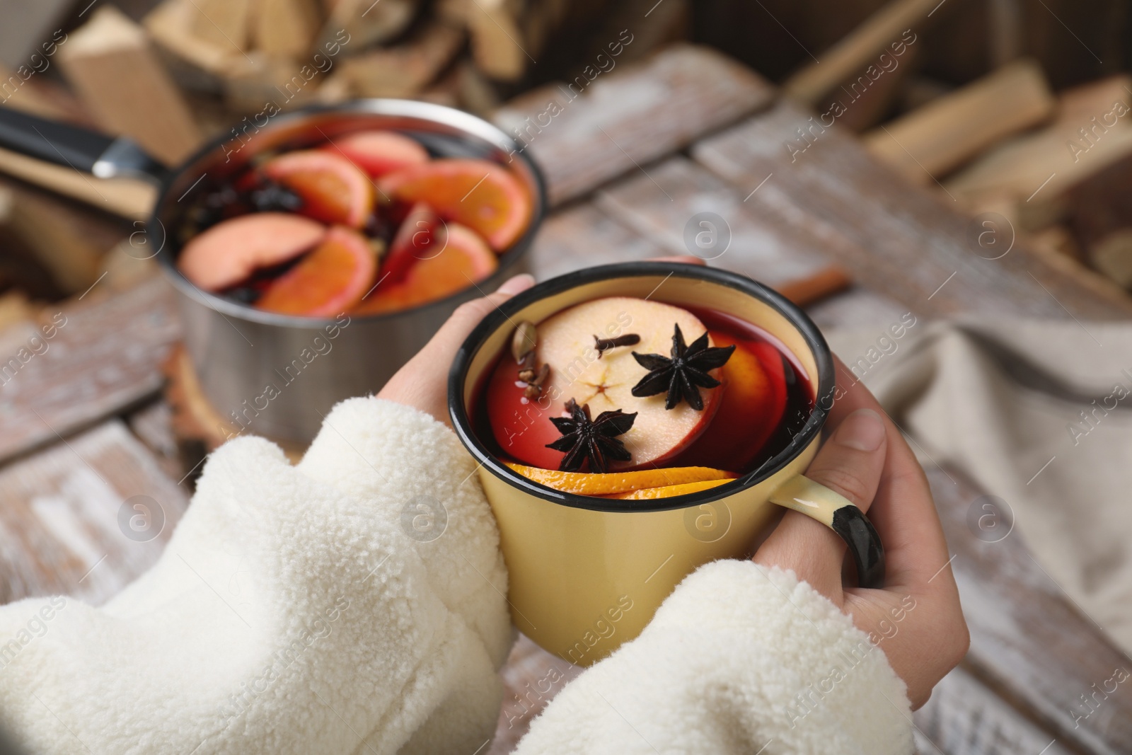 Photo of Woman with cup of delicious mulled wine at table, closeup