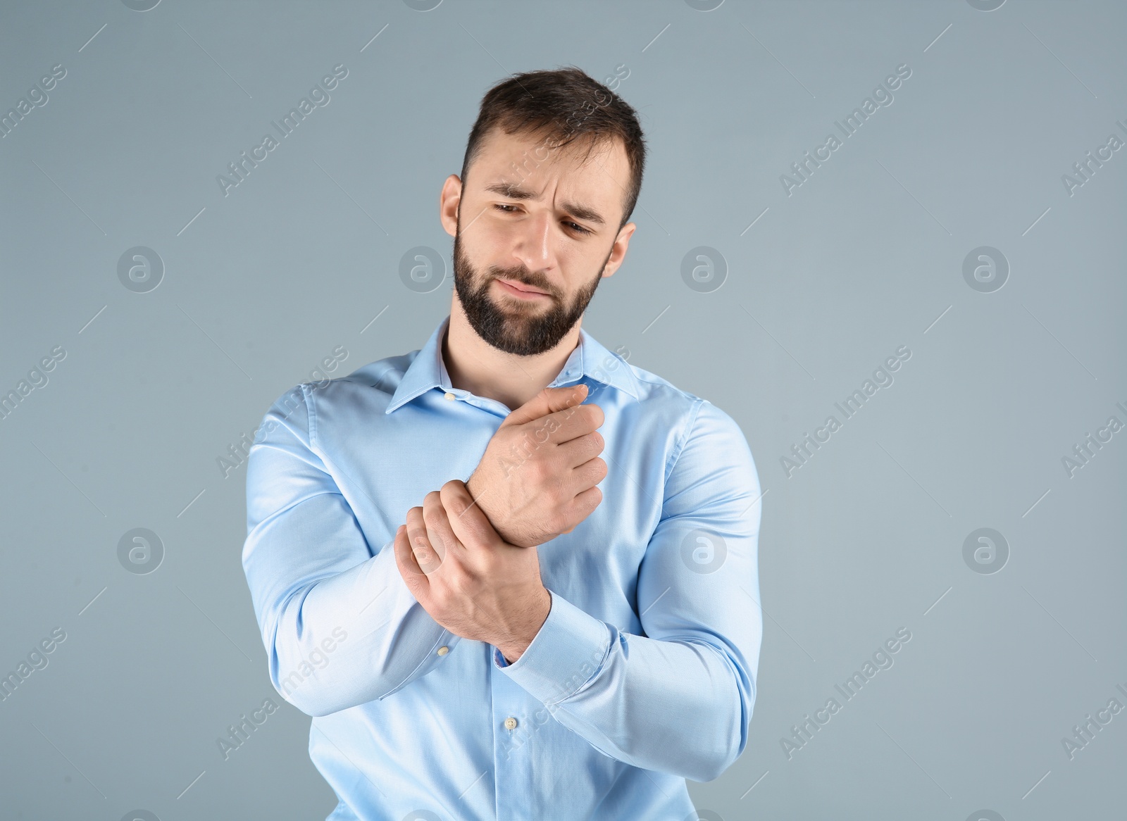 Photo of Young man suffering from pain in wrist on light background
