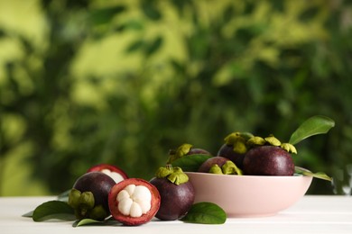 Photo of Delicious ripe mangosteen fruits on white wooden table outdoors, space for text