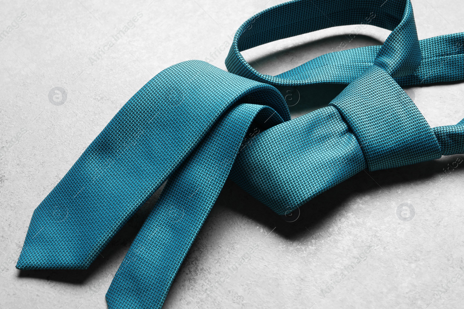 Photo of One blue necktie on light textured table, above view