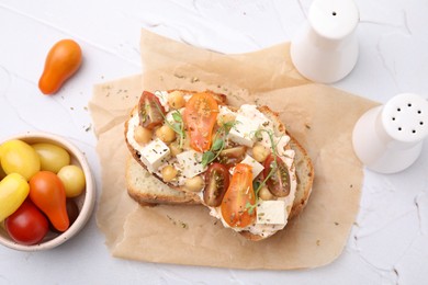 Photo of Tasty vegan sandwich with tomatoes, tofu and chickpeas on white textured table, flat lay