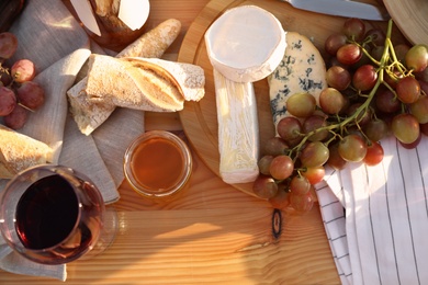 Red wine and snacks served for picnic on wooden table, flat lay