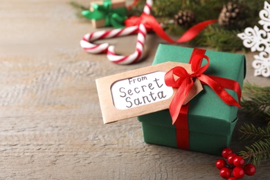 Photo of Present from secret Santa and Christmas decor on wooden table, space for text
