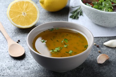 Photo of Bowl with lemon sauce on grey table. Delicious salad dressing