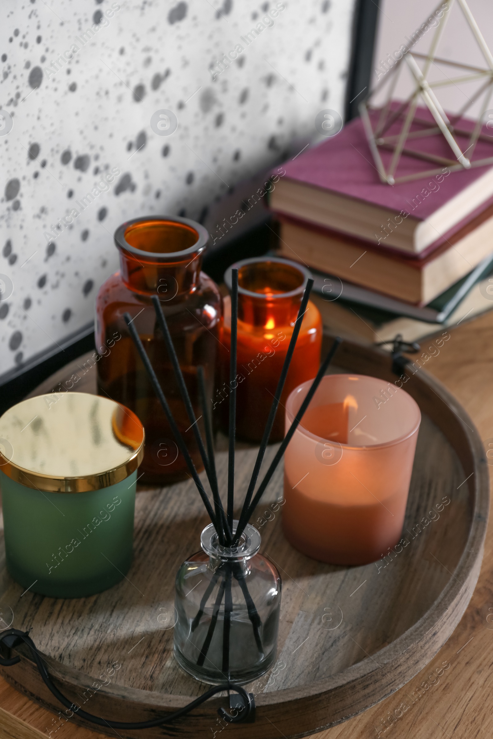 Photo of Wooden tray with air reed freshener and candles on table indoors