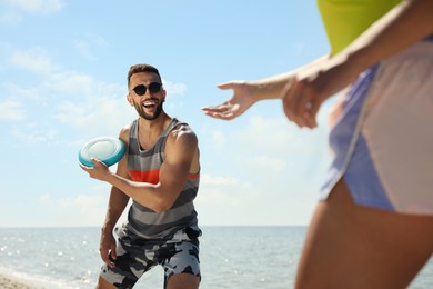 Couple playing with flying disk at beach on sunny day