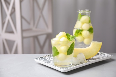 Photo of Tasty melon ball drink on grey table indoors. Space for text