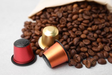 Bag with coffee capsules and beans on light grey table, closeup