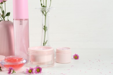 Homemade cosmetic products and beautiful flowers on white wooden table. Space for text