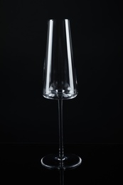 Photo of New empty champagne glass on black background