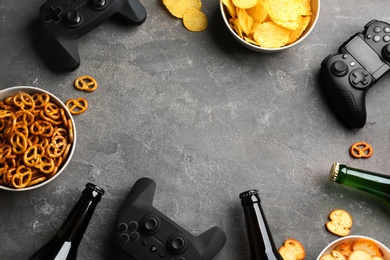 Photo of Flat lay composition with video game controllers, snacks and space for text on grey background