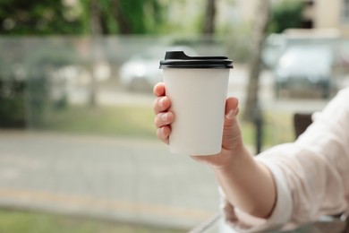 Photo of Woman holding paper takeaway cup outdoors, closeup with space for text. Coffee to go