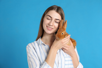 Photo of Young woman with adorable rabbit on blue background. Lovely pet