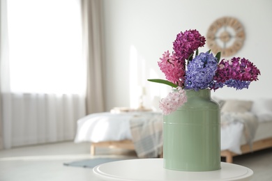 Photo of Beautiful hyacinths in metal can on table indoors, space for text. Spring flowers