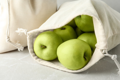 Photo of Cotton eco bags with apples on marble table, closeup