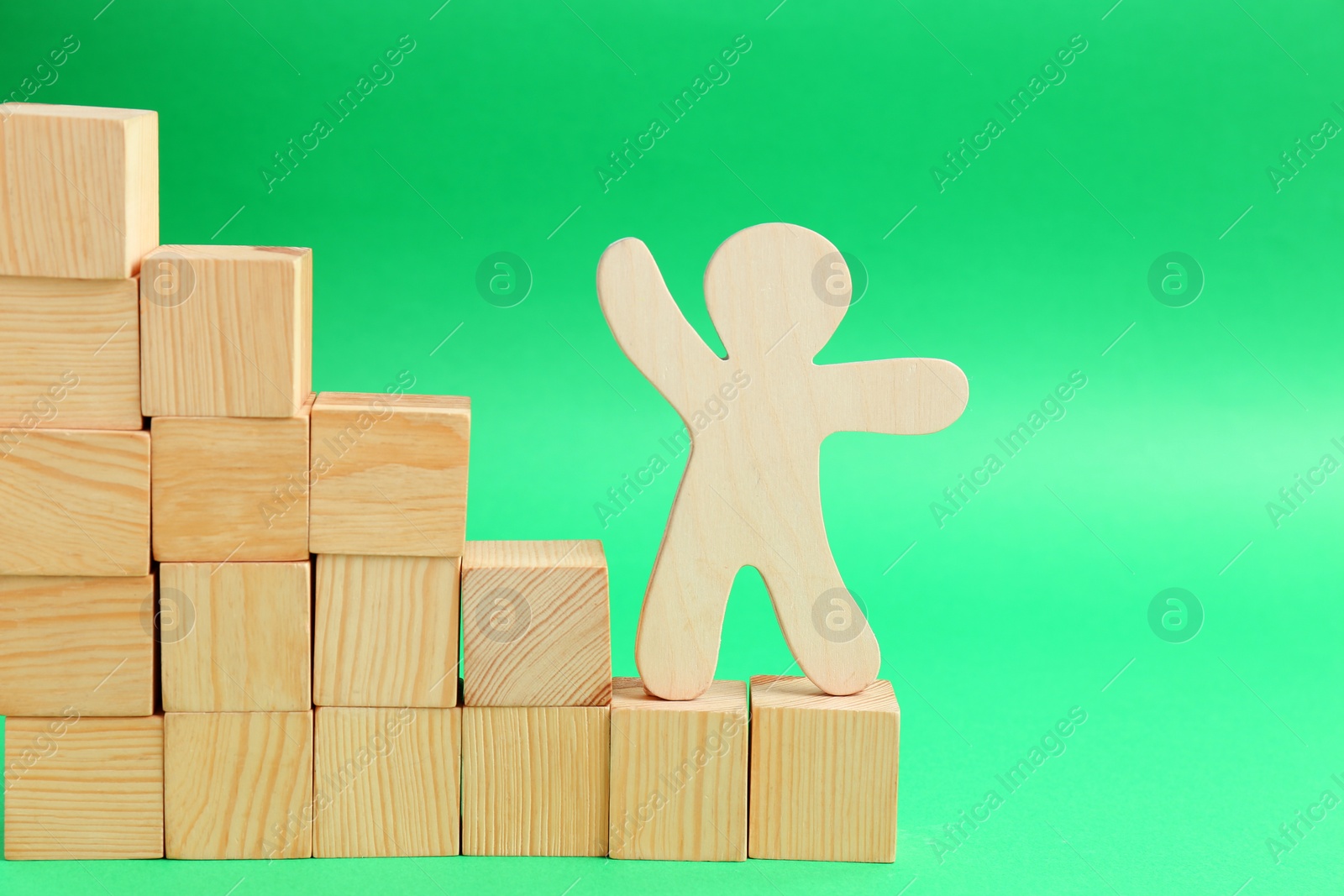 Photo of Wooden steps and human figure on green background. Social role concept