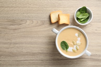 Photo of Healthy cream soup high in vegetable fats, bread and spinach on wooden table, flat lay. Space for text