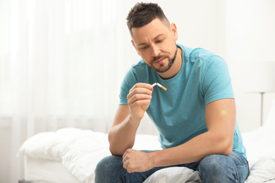 Photo of Man with nicotine patch and cigarette in bedroom