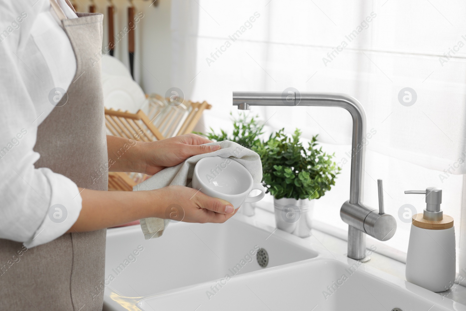 Photo of Woman wiping cup with towel in kitchen, closeup