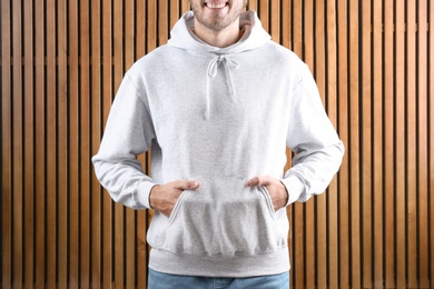 Man in hoodie sweater on wooden background. Space for design