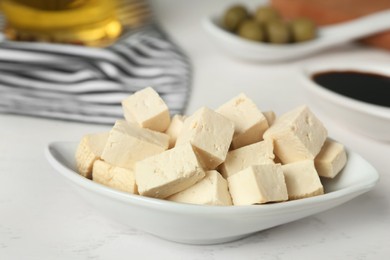 Photo of Pieces of delicious tofu on white table, closeup. Soybean curd