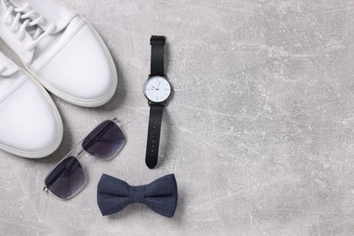 Photo of Stylish blue bow tie, shoes, sunglasses and wristwatch on light grey table, flat lay. Space for text