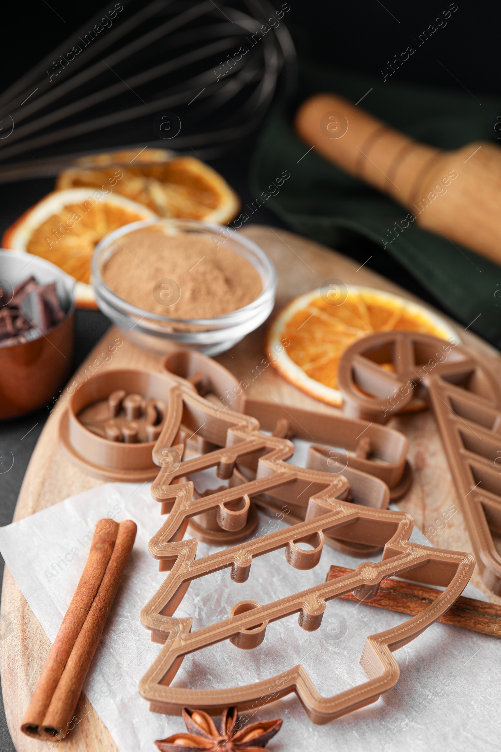 Photo of Different cookie cutters and ingredients on black table. Christmas treat